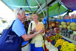 Couple choose fruit at a market on Oceania Cruises culinary tour